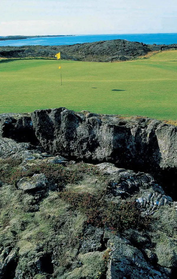 Golfer teeing off beside the ocean at Keilir Golf Club