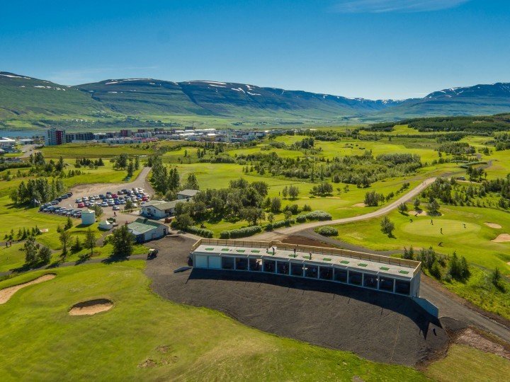 Aerial view of Ja&eth;arsv&ouml;llur's clubhouse and driving range with mountains behind