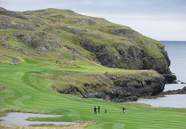 Golfers walking beside the coastal cliffs at Brautarholt Golf Club