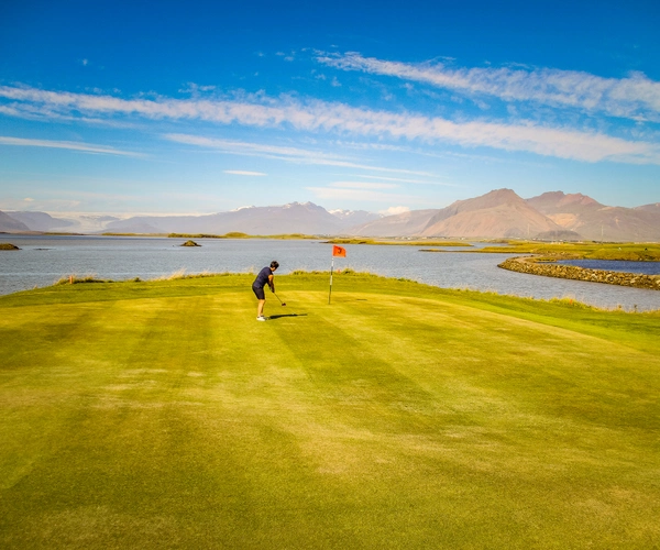 Golfer putting beside the water at Ekkjufellsv&ouml;llur