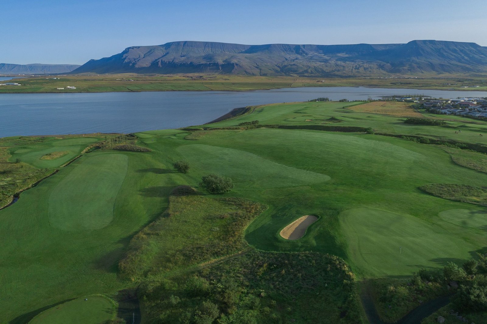 Fairway at Hl&iacute;&eth;av&ouml;llur beside the bay with mountains in the background