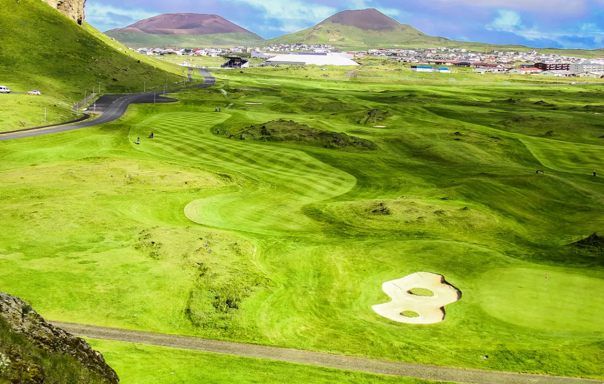 Aerial view of Vestmannaeyjar Golf Course with the town and craters in the background